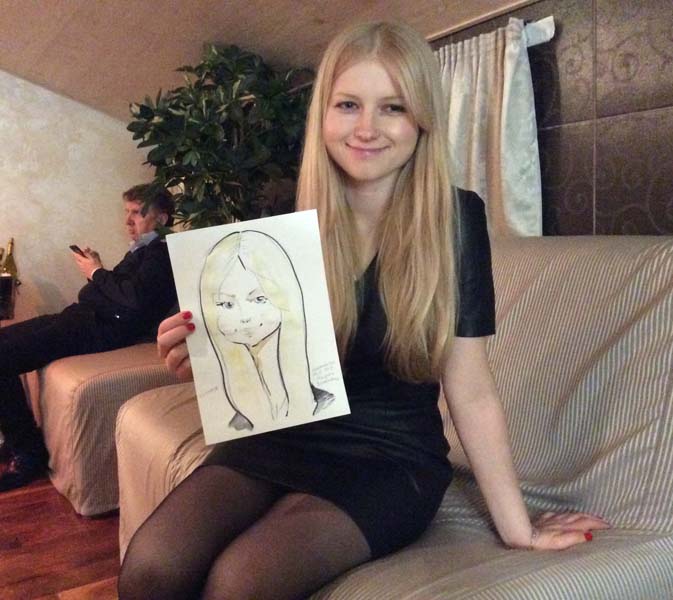 Ксения улыбантся держа свой шарж от Мишеля