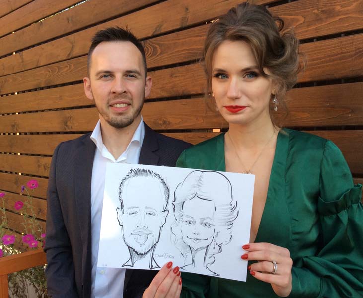 Саша и Юля держат свой шарж от МИхаила Шабалина на свадьбе